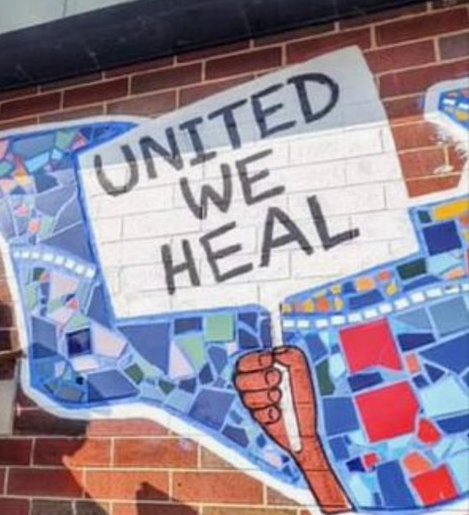 Graffiti art of a hand holding a sign that reads "United We Heal"